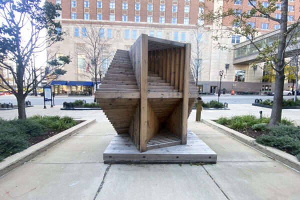 A large outdoor sculpture on a city sidewalk.